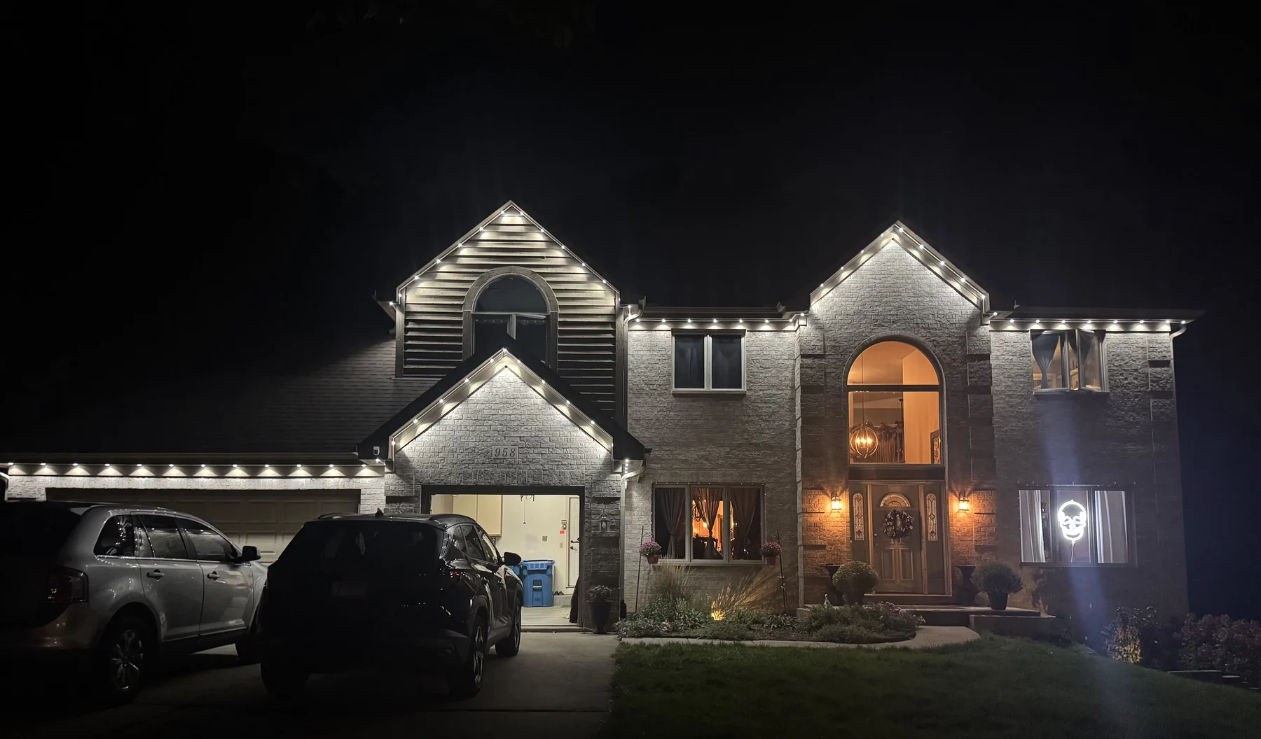 Two-story home at night with crisp white lights along the roofline and gables